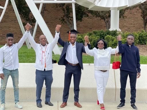 Jeremy Atuobi stands with four other members of his family, all with hands in the air, on graduation day.