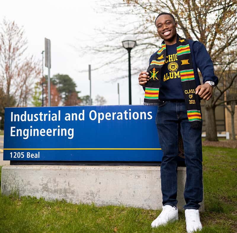 Jeremy Atuobi stands in front of the Industrial and Operations Engineering sign on 1205 Beal Street.