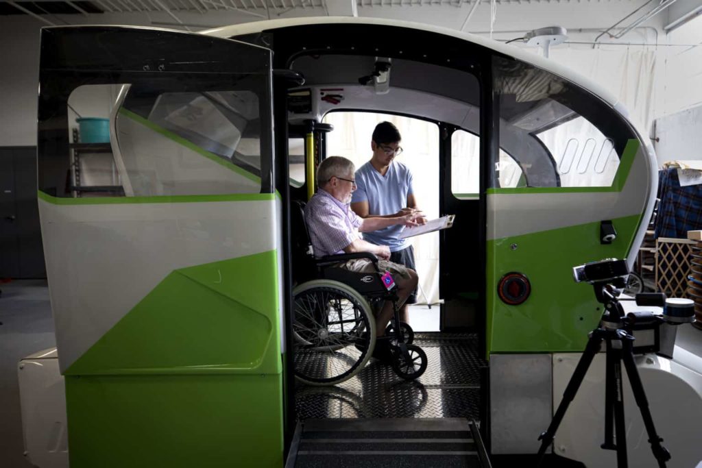 Person in wheelchair in an oversized vehicle looking at a person with clipboard