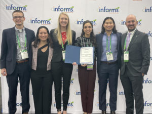 People stand with an award at the 2022 INFORMS Annual Meeting