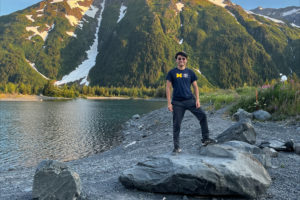 Nick Tran standing on a boulder in front of a lake and mountain