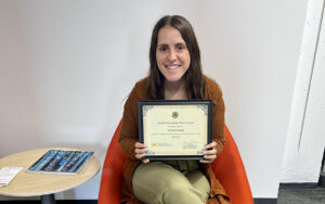 Leonora Lucaj holds up her Outstanding Advisor Award