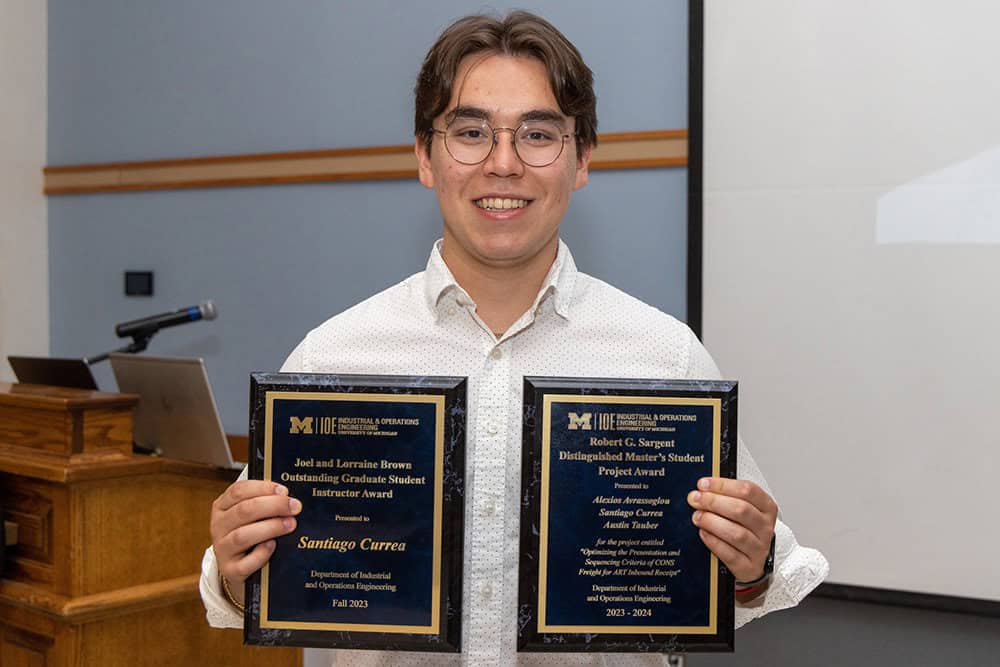 A person holding two award plaques