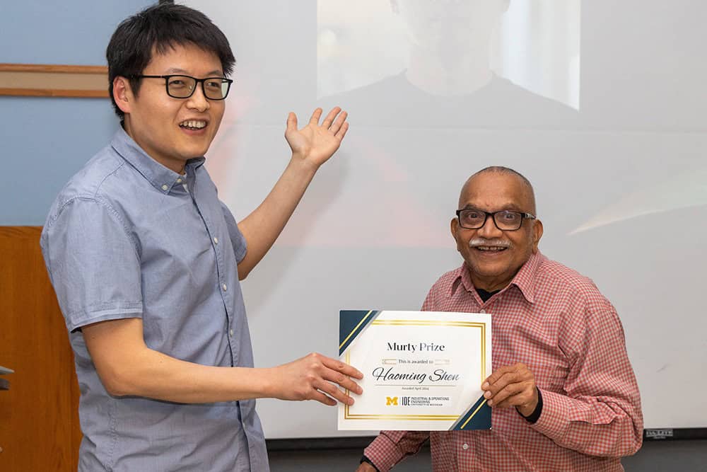 A man holding a certificate hands it to another man