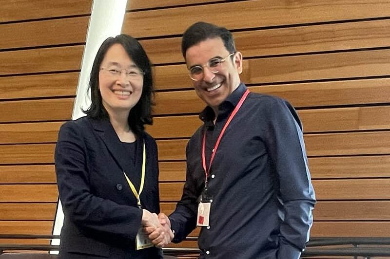 Saif Benjaafar shakes hands with an Asian Woman at a confernce. The background is of the large modern wood walls.