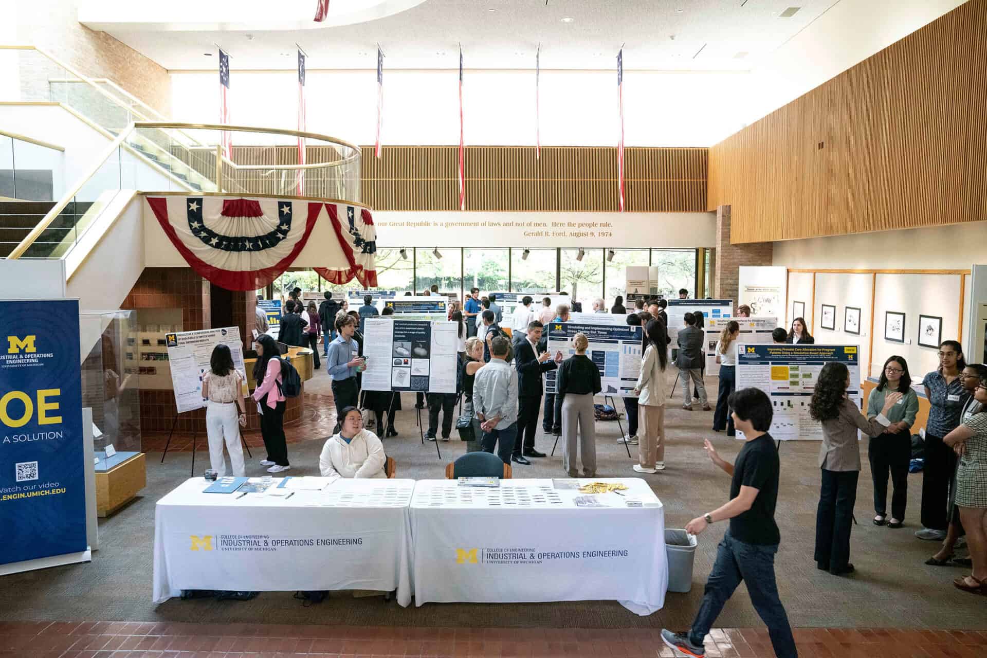 Many people walk around a large open room viewing research posters