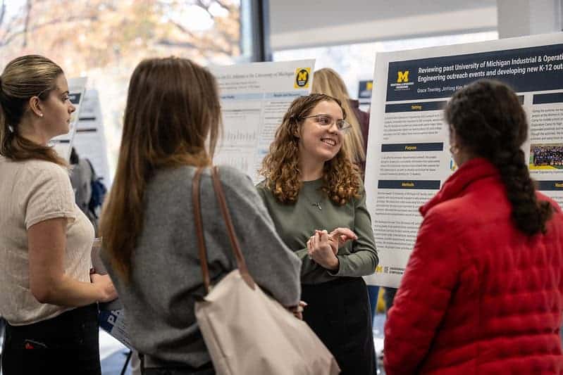 four people look at a research poster