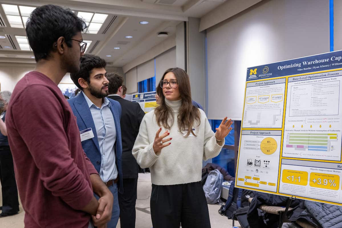 Three students looking at research poster