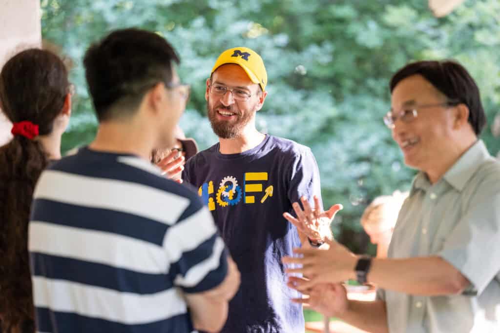 Albert Berhas talking to two other people in IOE shirt