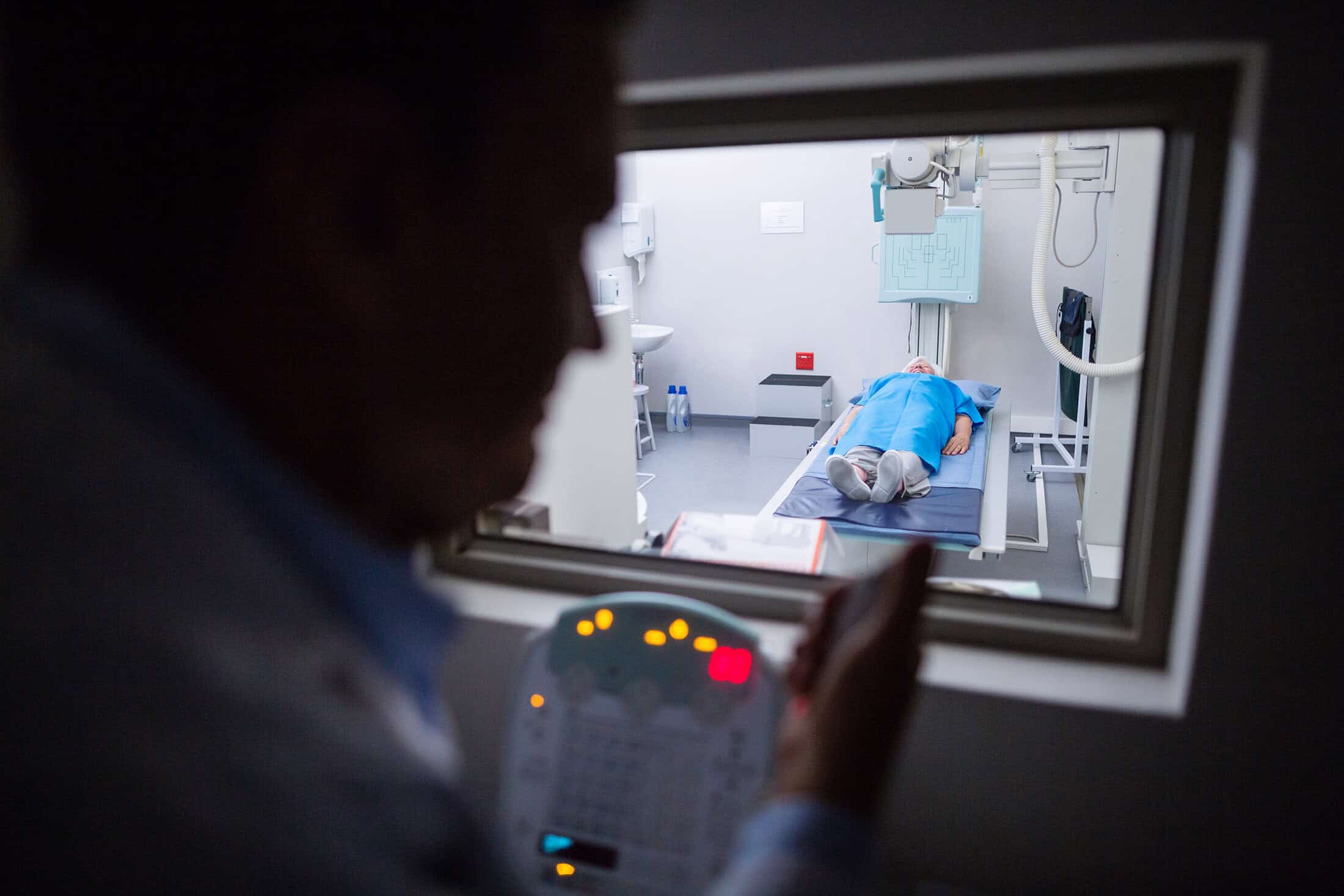 Doctor using x-ray unit control panel on patient in hospital