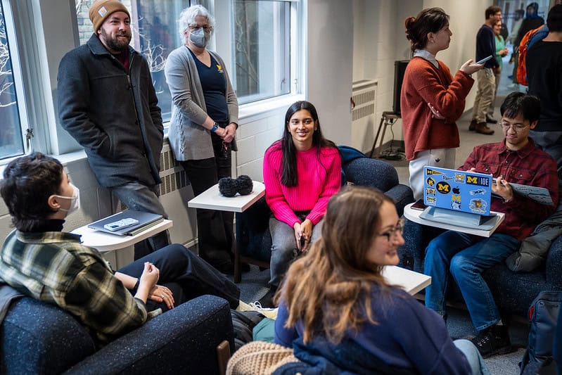 Several people sit in a circle talking to one another